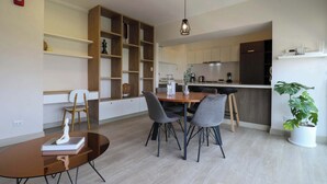 A modern kitchen with wooden cabinets, a dining area with a round table and chairs, and a potted plant. - w*| Comfy 2BR w/ Park View  in Miraflores (Lima)