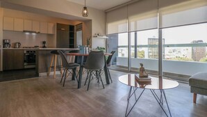 A modern kitchen with a dining area, large windows with a city view, and a small table with a statue. - w*| Comfy 2BR w/ Park View  in Miraflores (Lima)