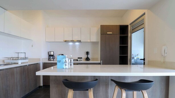 A modern kitchen with a central island, bar stools, and a built-in oven. - w*| Comfy 2BR w/ Park View  in Miraflores (Lima)
