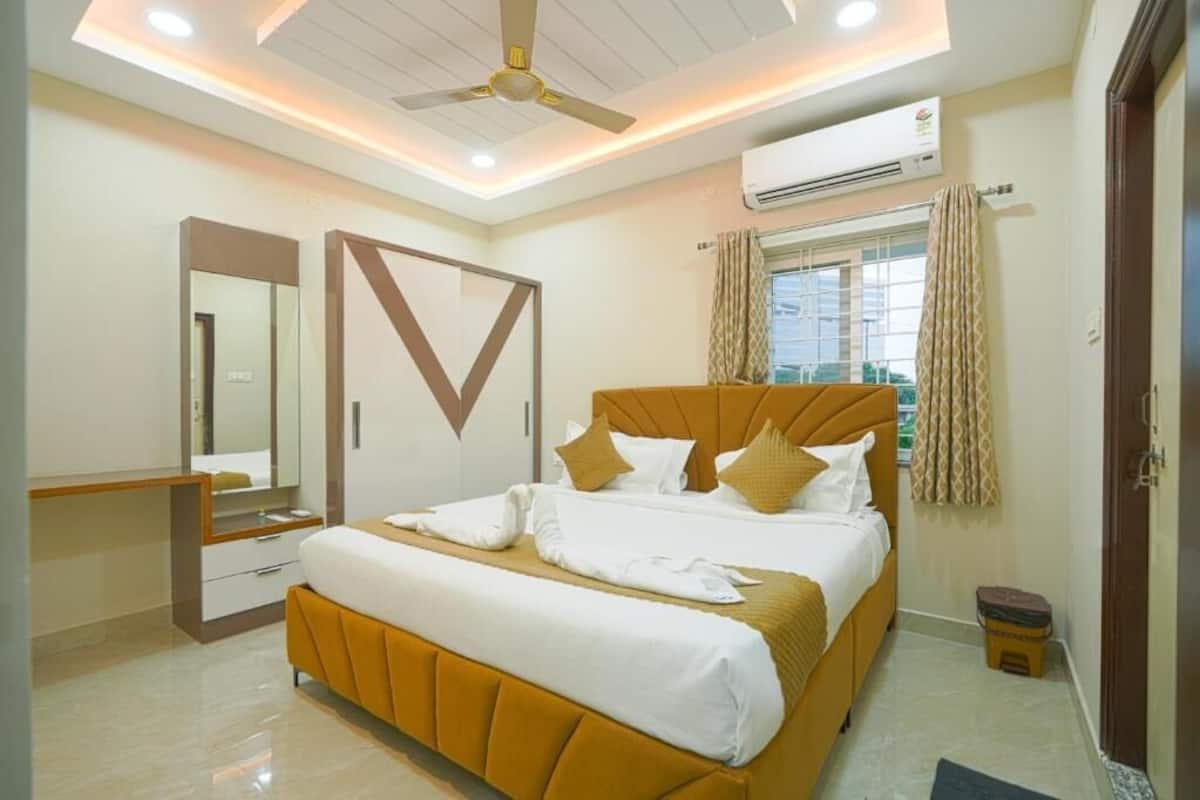 Une chambre d’hôtel moderne dotée d’un grand lit, d’un ventilateur de plafond, d’un appareil de climatisation et d’une fenêtre avec des rideaux.