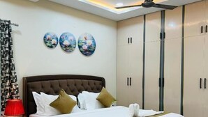 Une chambre moderne avec un grand lit, un ventilateur de plafond et une armoire.