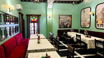 Un restaurante con una barra larga, asientos rojos, candelabros y decoración en las paredes.