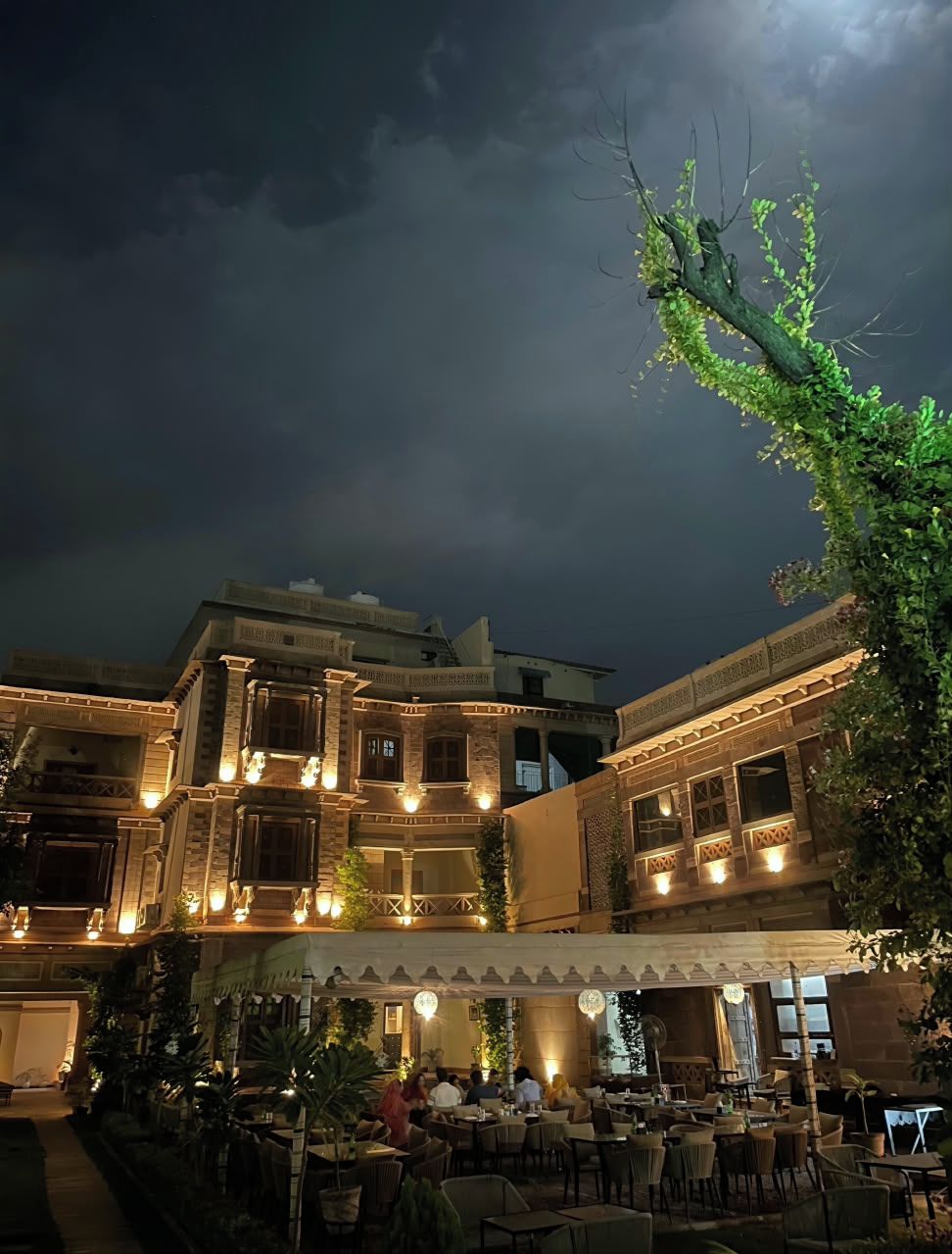 An outdoor dining area with tables and chairs, surrounded by a building with multiple levels and balconies.