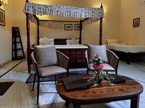 A four-poster bed with a canopy, two upholstered chairs, a small table with a vase, and a nightstand. - RAGHVENDRA HERITAGE (Jodhpur)
