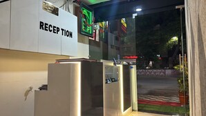 A reception area with a sign labeled "RECEPTION" and a neon sign above the door. - Hotel Apple INN (Indore)