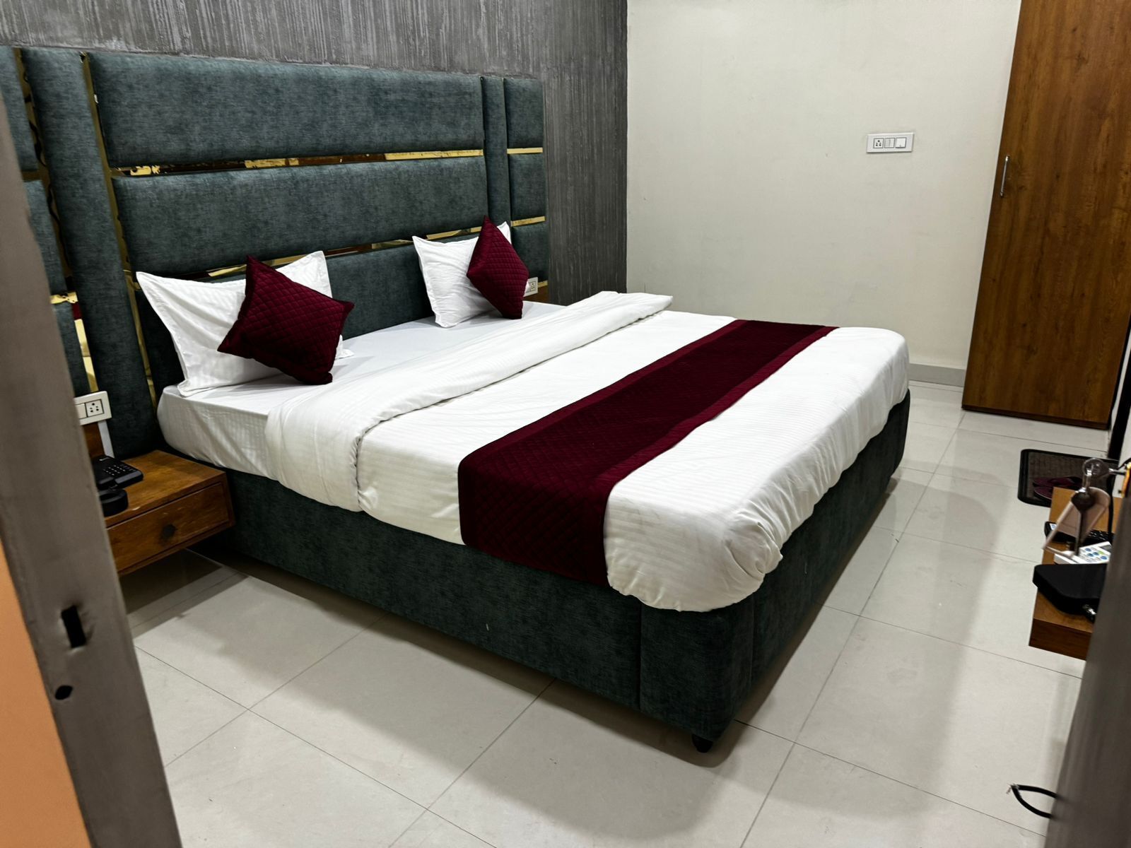 A neatly made bed with a dark headboard, white linens, and a red throw blanket.