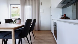 A modern kitchen with a wooden table, black chairs, and a built-in oven. - Cosy Riverside Escape with River Views (Riverside)