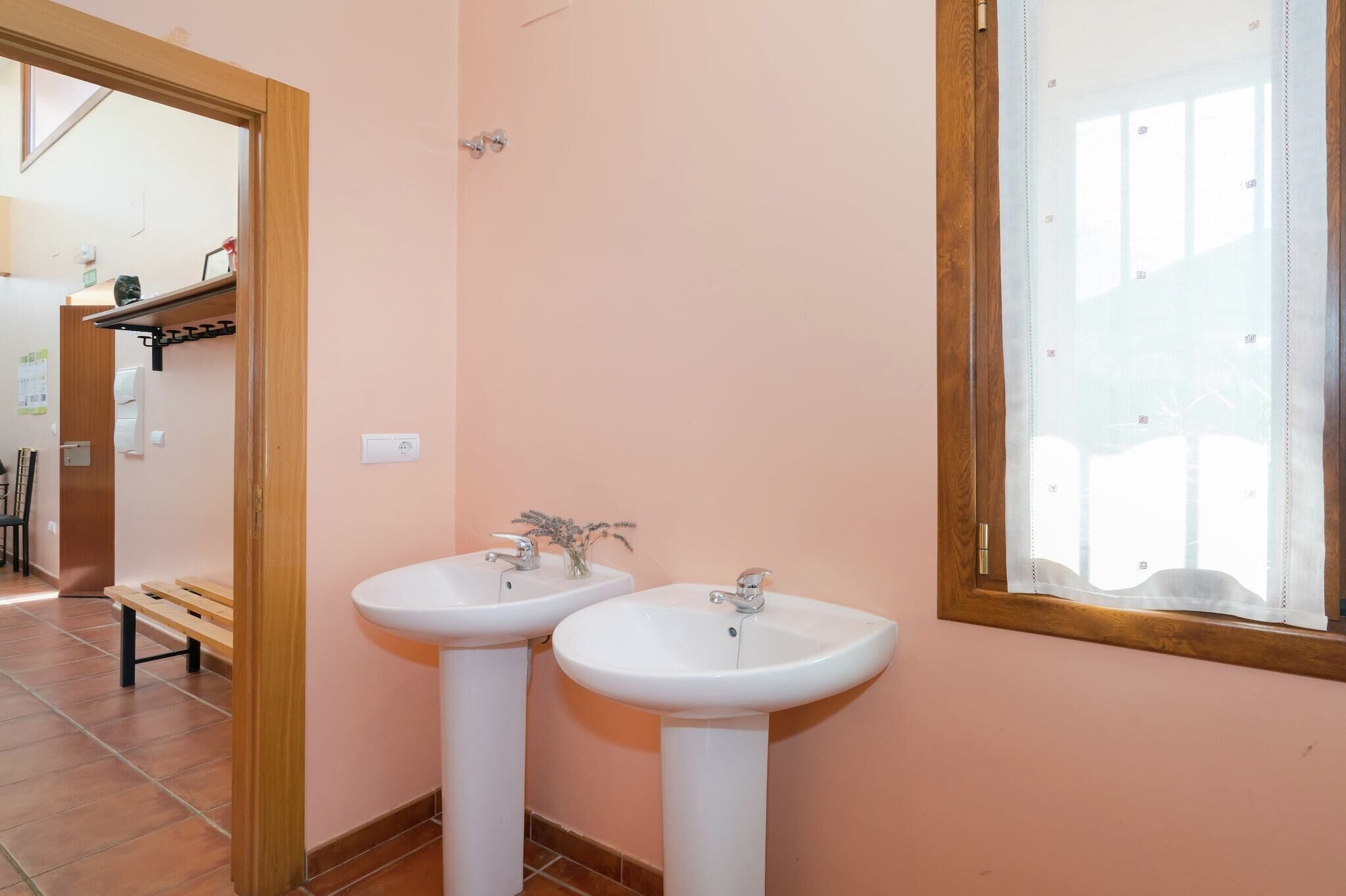 A bathroom with two white sinks, a wooden bench, and a mirror with a wooden frame.