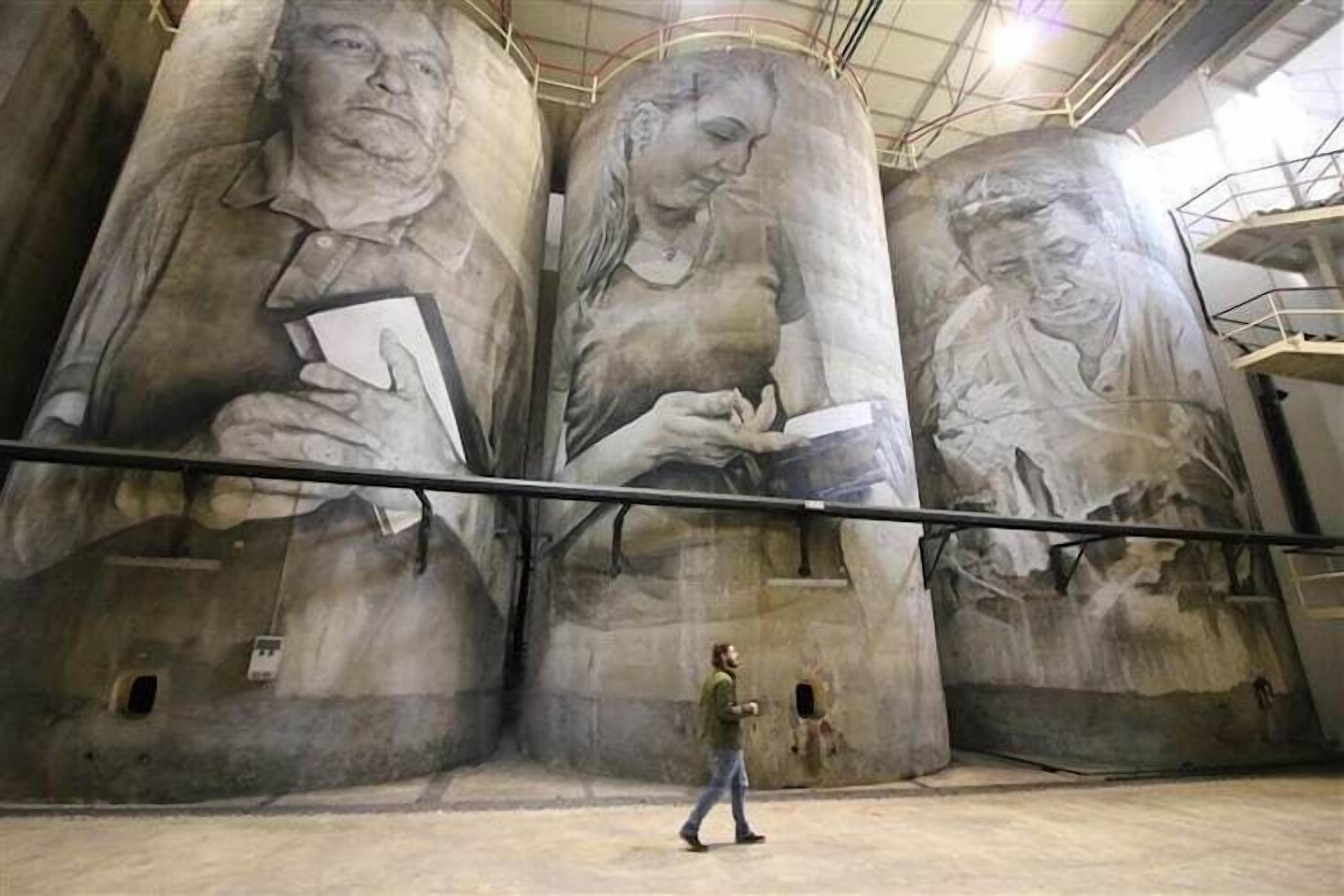 A large mural with three figures holding books, a person walking in front, and a staircase to the right.