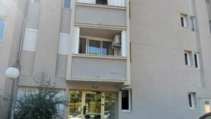 A multi-story building with a ground-level entrance, a parking area, and a car parked in front.