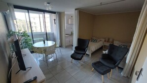 A compact living space with a dining area, a small kitchenette, and a bedroom.