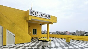 A hotel named HOTEL AAVAS with a yellow exterior, a checkered floor, and a visible window. - HOTEL AVAAS TripandTrip (Puri)