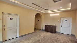A hallway with a marble floor, white doors, and a wooden cabinet. - HOTEL AVAAS TripandTrip (Puri)