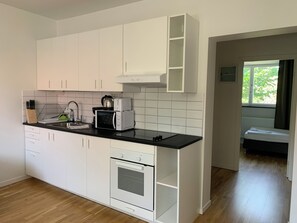 Una cuina moderna amb armaris blancs, tauleig negre i forn encastrat.