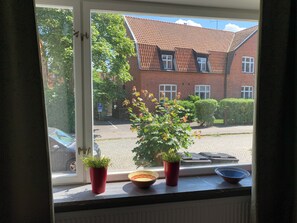 A window with a view of a brick building, a street, and a parked car. - Villa Nova (Lund)