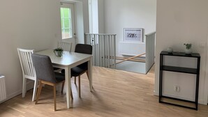 A dining area with a table and chairs, a radiator, a window, and a picture frame on the wall. - Villa Nova (Lund)
