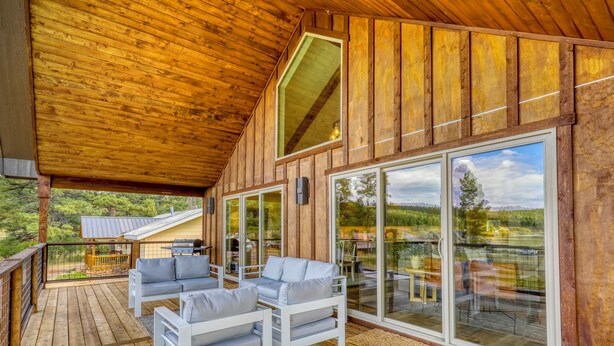 Une terrasse en bois avec des sièges extérieurs et de grandes portes vitrées donnant sur un paysage magnifique.