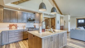 Une cuisine spacieuse avec des meubles en bois, un îlot central et des luminaires suspendus.