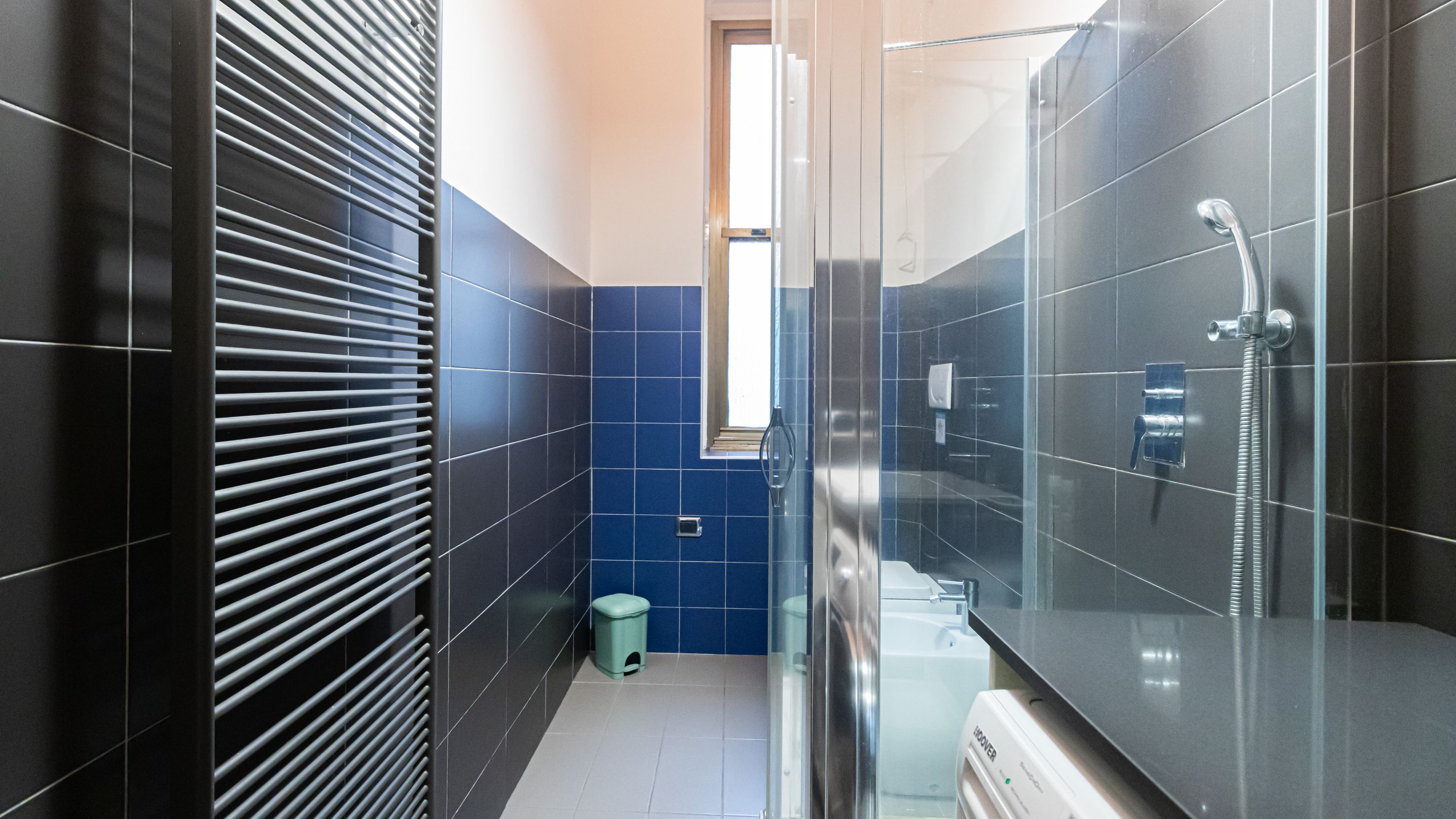 Un baño moderno con cabina de ducha de vidrio, inodoro y cubo de basura.