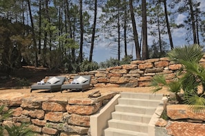 A stone staircase leading to a seating area with two lounge chairs and a stone wall.