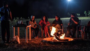 A group of people seated around a campfire at night. - Tusker Valley Resort (Sakleshpur)