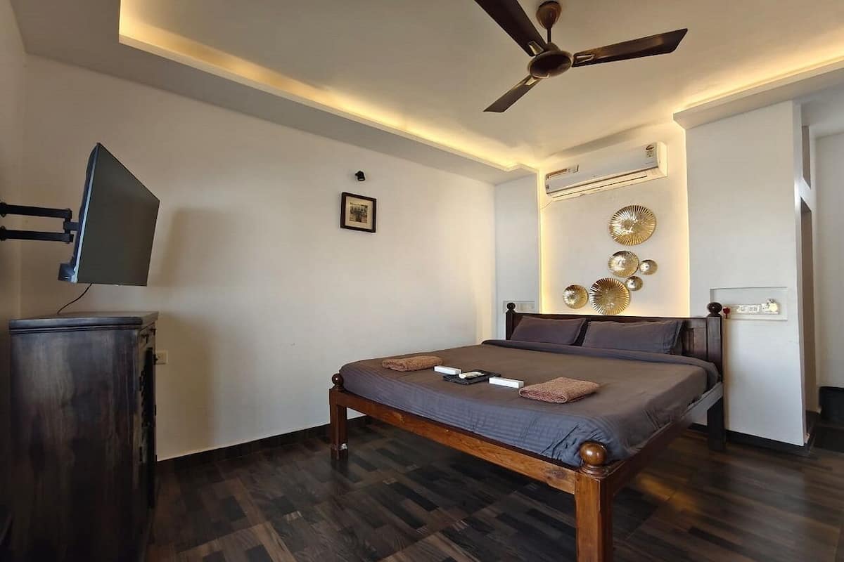 A bedroom with a wooden bed, a ceiling fan, a flat-screen TV, and decorative wall art.