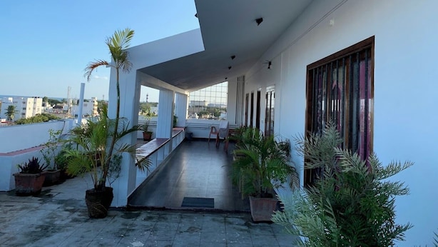 A covered outdoor area with potted plants, a staircase, and a view of the cityscape. - The French Villa Elite (Puducherry)