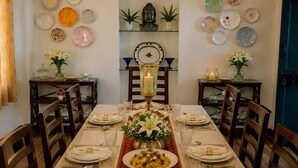 A dining room with a long table set for a meal, surrounded by chairs. - AM Hotel Kollection Maangarh Ratlam (Ratlam)