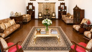 A traditional living room with a chandelier, sofas, armchairs, a coffee table, and framed pictures on the walls. - AM Hotel Kollection Maangarh Ratlam (Ratlam)