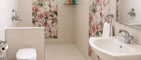 A modern bathroom with a toilet, sink, shower, and a water heater.