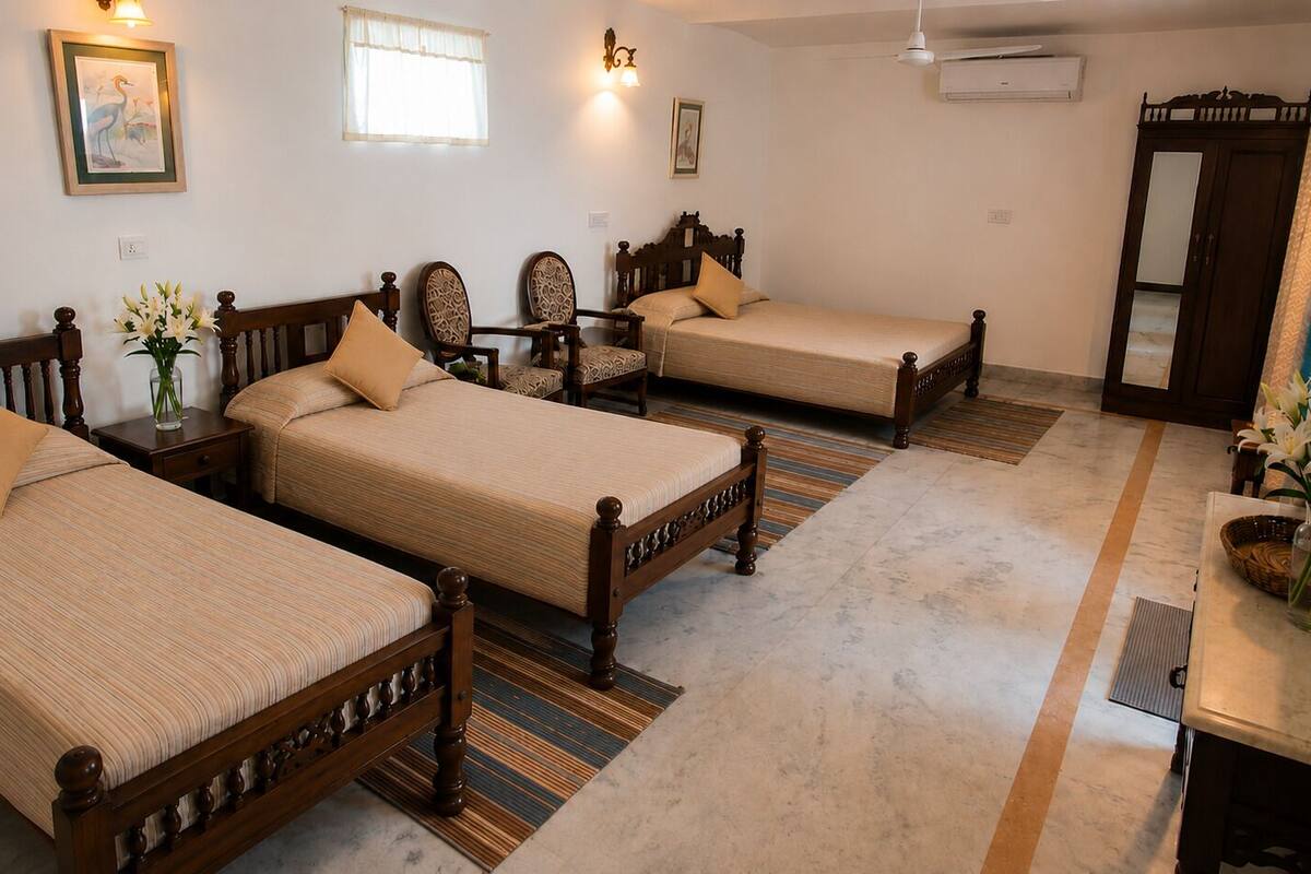 A hotel room with three wooden beds, a small table, a chair, and a wardrobe.