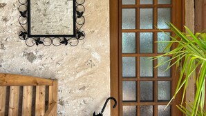 A rustic wooden door with frosted glass panels, a metal-framed mirror with a leaf design, and a wooden bench.