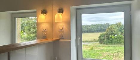 A bathroom with a large window, a mirror, a sink, and two wall-mounted lights.