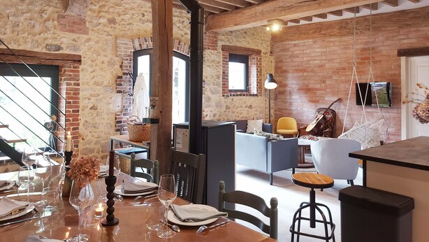 Un coin repas au style rustique, avec des murs en briques apparentes, des poutres en bois et un escalier en pierre.