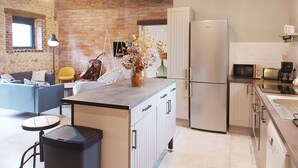 Une cuisine moderne dotée d’un îlot central, d’appareils électroménagers en acier inoxydable et d’un luminaire suspendu.