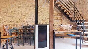 A rustic interior with a stone wall, a modern fireplace, wooden furniture, and a staircase.