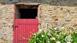 A rustic stone building with a red wooden door and a small opening above it. - Country house with terrace and fireplace, accessible for PRM, near water activities (Saint-Aignan-sur-Roë)