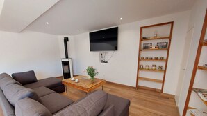 Un soggiorno moderno con un divano componibile, un tavolino in legno, una televisione a parete e una libreria con diversi oggetti.