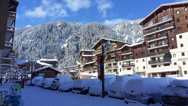 A snow-covered mountain town with wooden buildings and a clear blue sky.