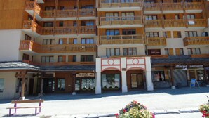 A multi-story wooden building with balconies, a central entrance, and shops on the ground floor.