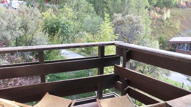 A wooden deck with two wooden chairs and a view of a forested area. - Cozy studio for 6, in the heart of the resort (Les Orres)
