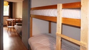 A bunk bed room with a wooden floor, a table with chairs, and a window with curtains. - Cozy studio for 6, in the heart of the resort (Les Orres)