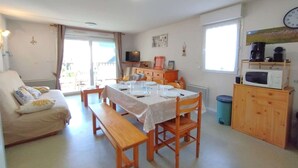Un espai vital compacte amb zona de menjador, sofà, televisió i petita cuina.