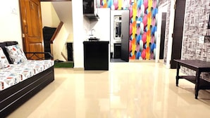 A spacious living area with a sofa, a dining table, and a kitchen area with a colorful wall.