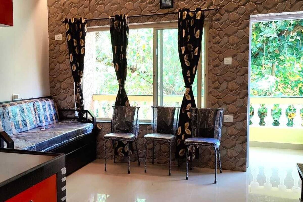 A living room with a sofa, chairs, a TV, and a stone wall.