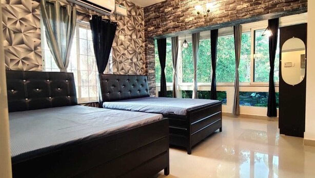 A bedroom with a bed, a dresser, and a large window with curtains.