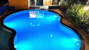 A swimming pool with a tiled deck and metal railings.