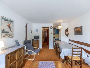 A cozy room with a wooden dining table, a blue chair, a wooden cabinet, and a ski-themed poster on the wall. - Studio cabin, balcony, 5 guests, near slopes (La Mongie)