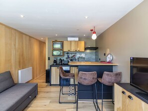 Cozy living space with a kitchenette, sofa, and bar area, featuring a television and modern amenities.