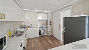 Een moderne keuken met witte kasten, een inbouwoven en een zwarte koelkast.